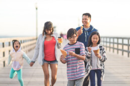 family walking down boardwalk and eating ice cream