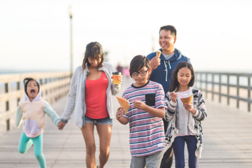 family walking down boardwalk and eating ice cream